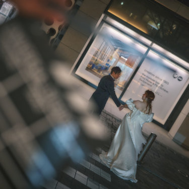 カチンコ越しに、手を取ってくるりと回る新郎とサテンのドレスの花嫁。映画のワンシーンのようなナイトウェディングフォト