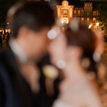 手前の新郎新婦をぼかし、遠くにライトアップされた東京駅の駅舎を写したおしゃれな構図のフォトウェディング