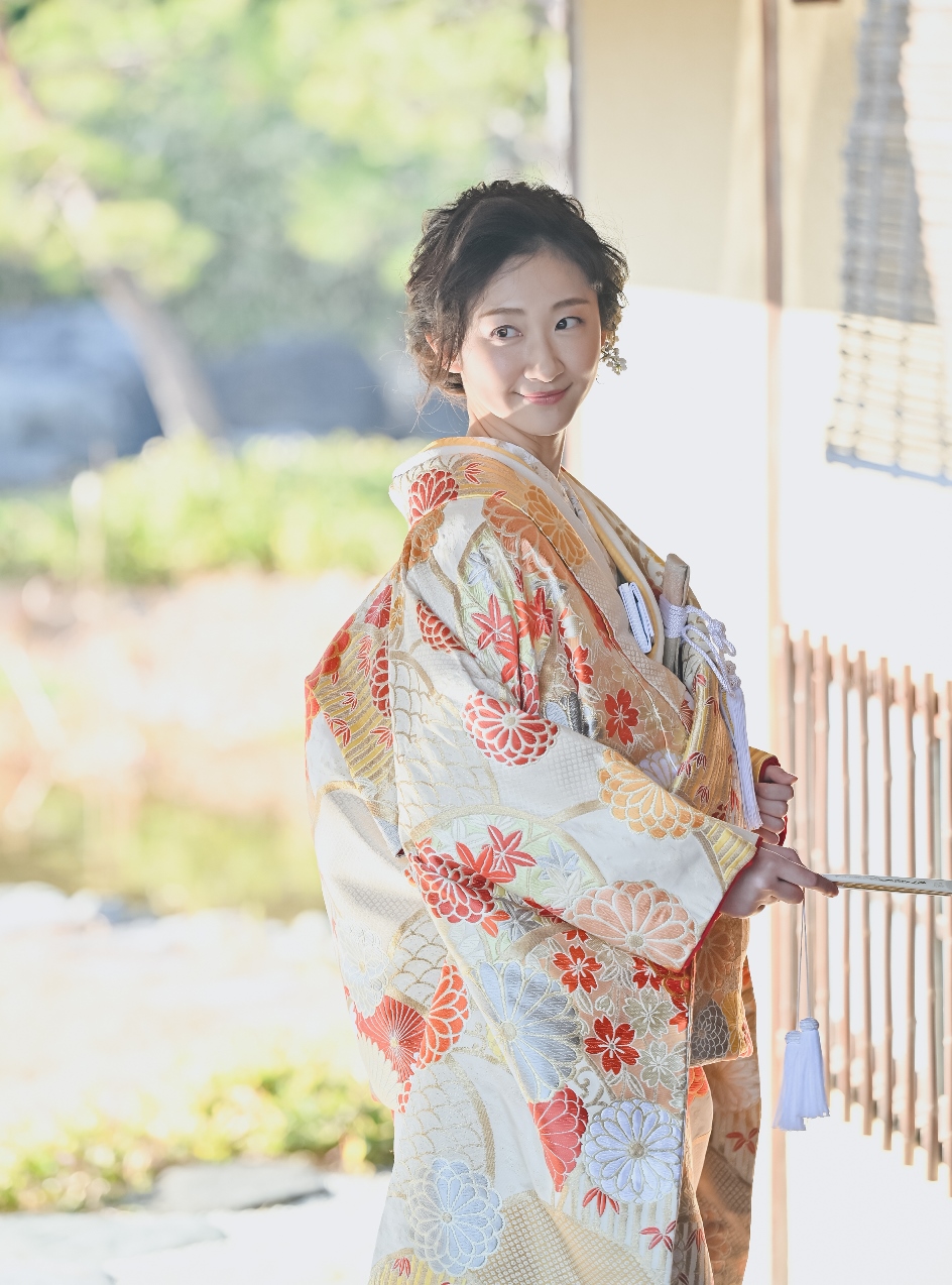 金糸の花柄が美しい色打掛を着た新婦が振り返るポートレート。