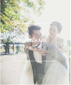 「Natural」プランのバナー、緑の中で新婦をおんぶする洋装の新郎新婦。