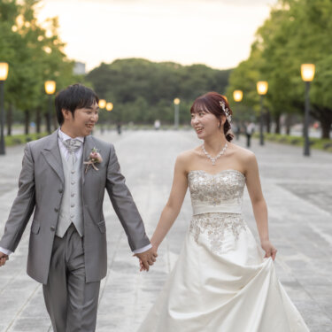 夕方の行幸通りで手をつないで見つめ合いながら歩く新郎新婦。ウェディングドレスとタキシードで撮る東京駅前のフォトウェディング