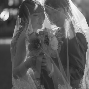 ベールの中で寄り添いブーケを抱える新郎新婦のモノクロ写真。東京駅丸の内のナイトフォトで撮る幻想的なウェディングフォト