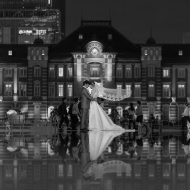 東京駅丸の内駅舎と新郎新婦が水鏡に映り込む、モノクロのリフレクション写真。夜の東京駅で撮るドラマチックな洋装前撮り