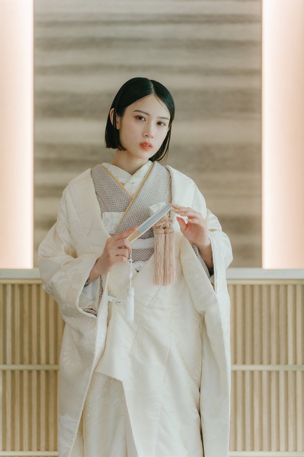 金の縁取りの掛下に白無垢を重ね、末広を手にした花嫁のポートレート。フォトウェディングで選ばれる上品な白無垢コーディネート